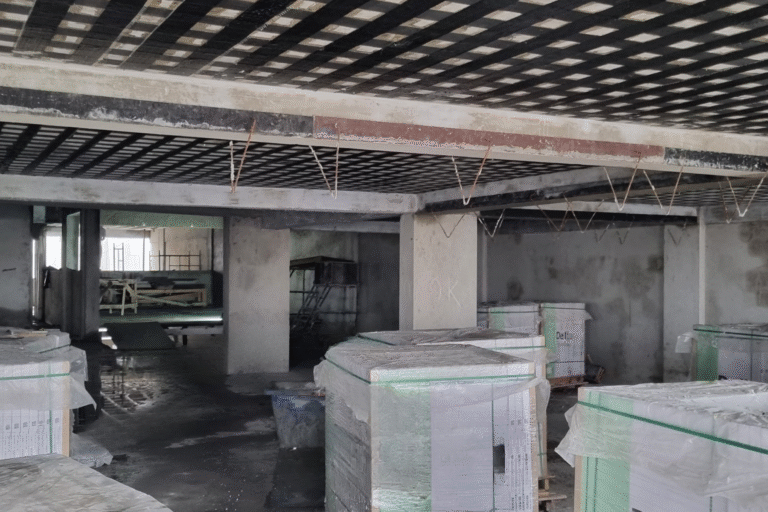 Aplicação de laminados de fibra de carbono (CFRP) para reforço estrutural de vigas e lajes de concreto armado em edificação em construção.